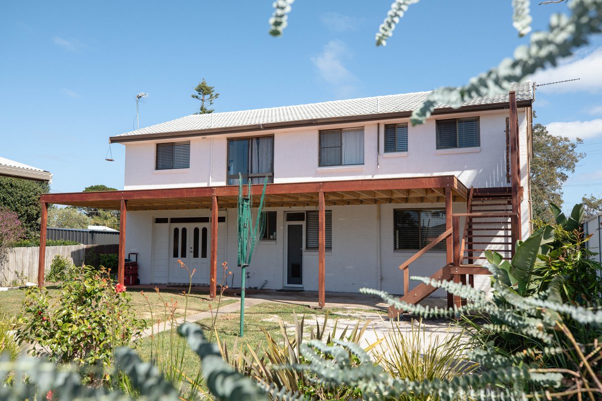 An elevated deck and outdoor stairs beside a two-storey house, with open edges and exposed framing.