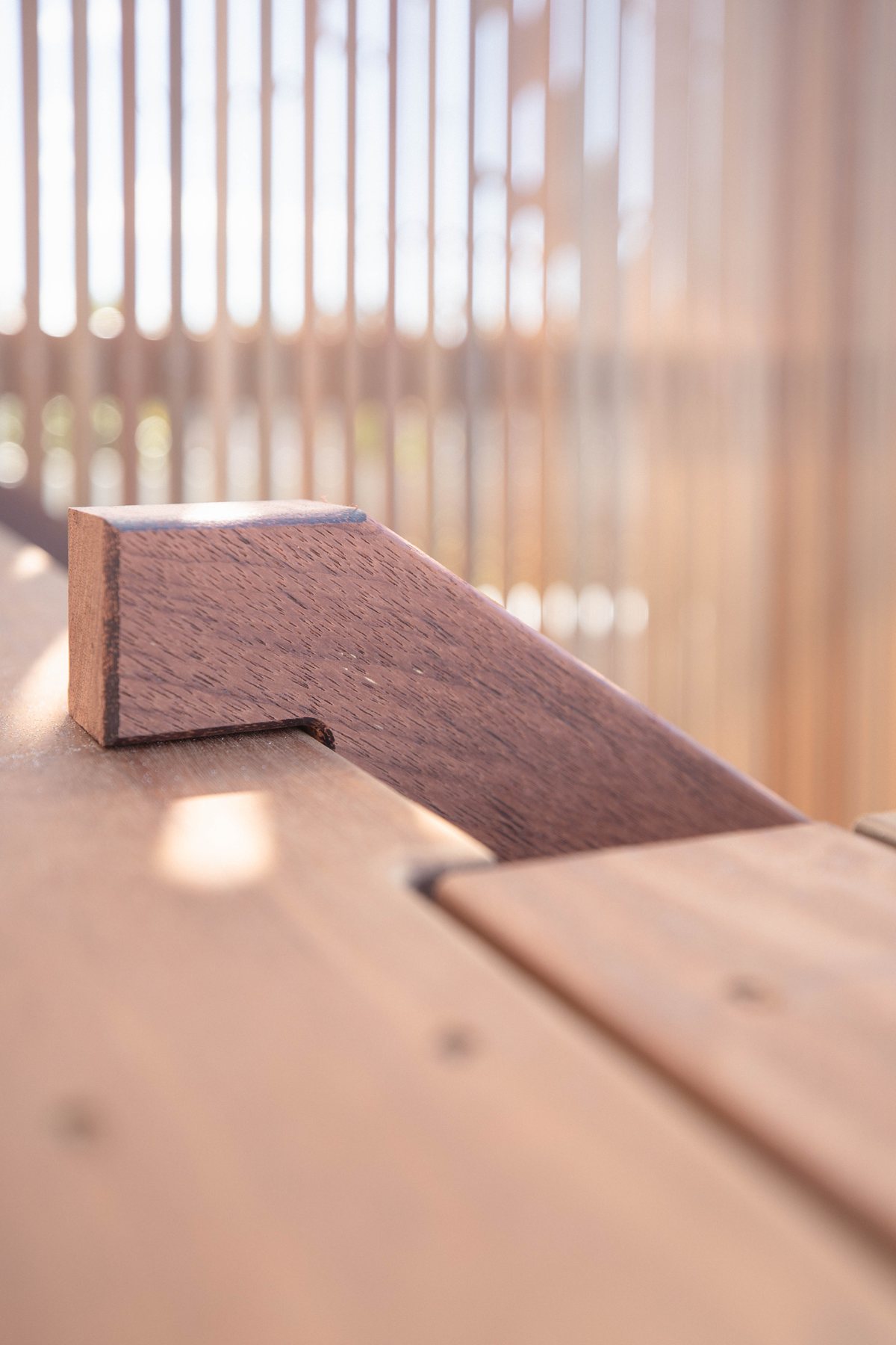 A close view of a timber joint with a slatted screen in the background.