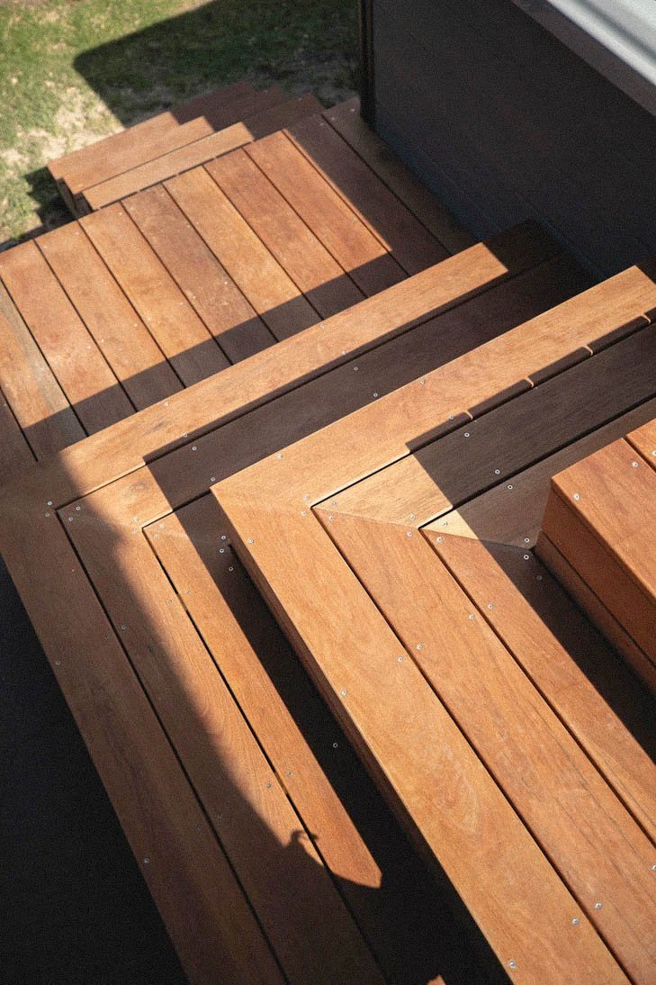 Close view of timber steps and angled border boards at a deck corner.