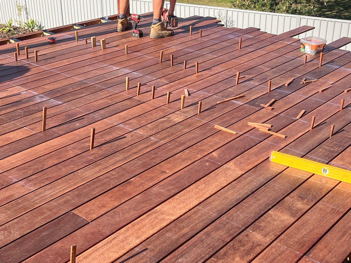 Timber decking boards with spacers between them, with drills and a spirit level on the surface.