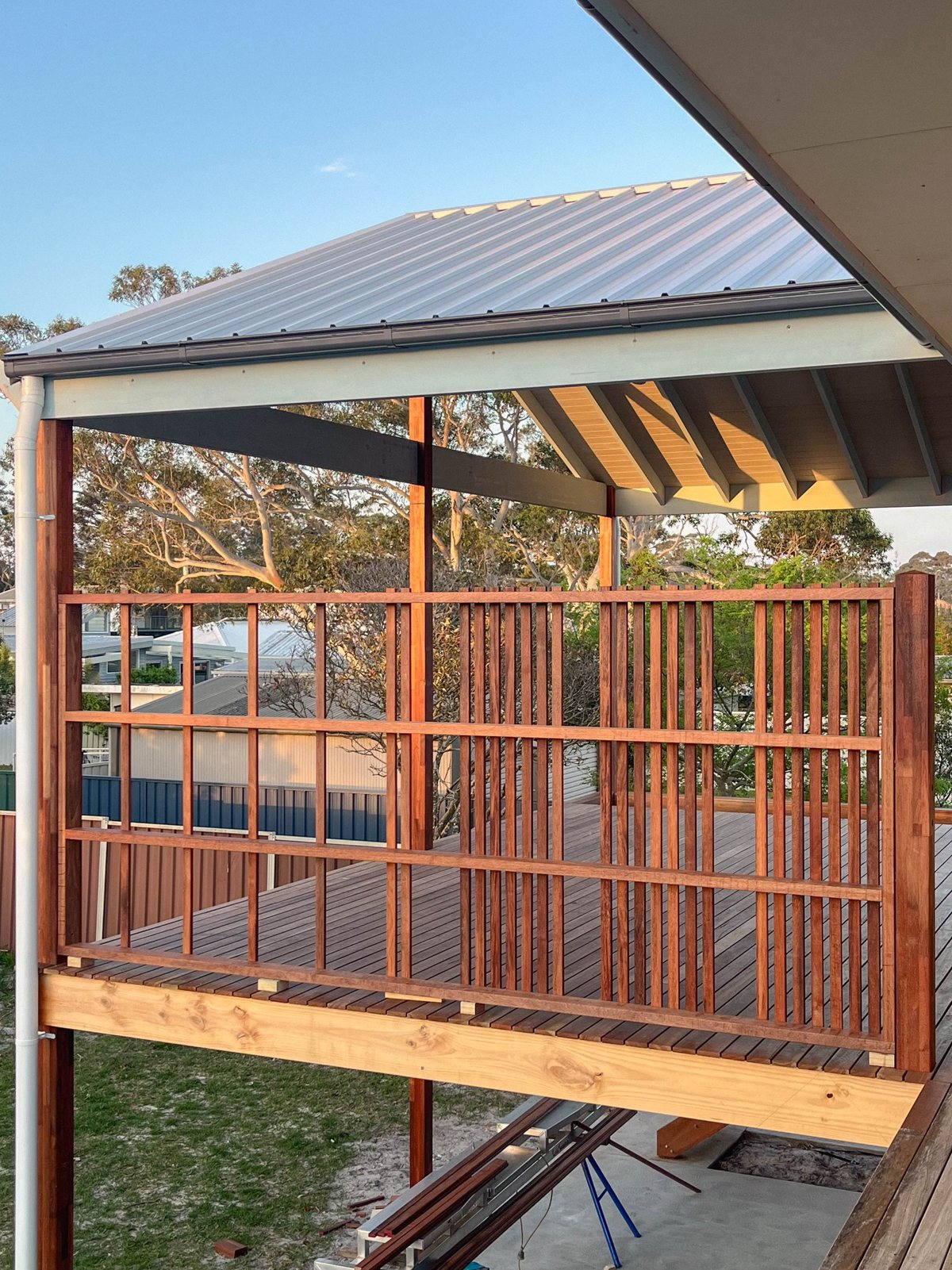 A covered timber deck with vertical balustrade boards, viewed from beside the house.