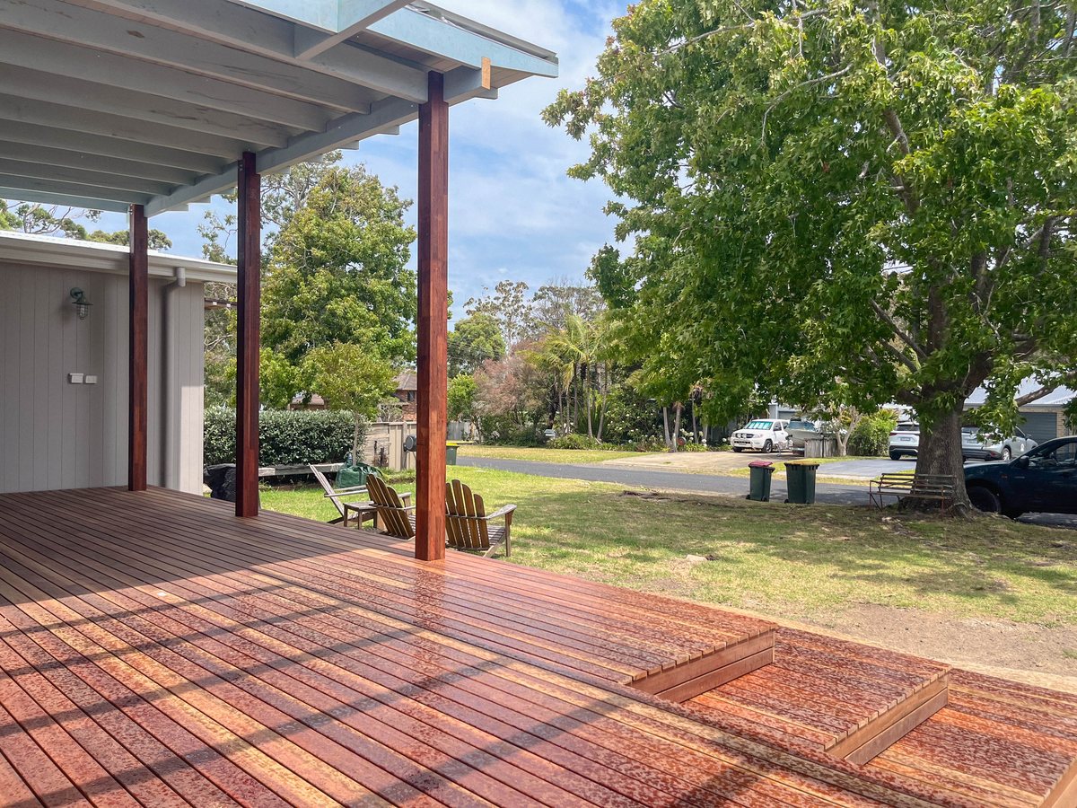 A timber deck with wide steps and timber posts beneath a pale single-pitch roof.